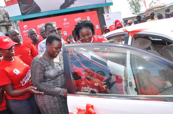 Airtel's Head of Brand and Communication Remmie Kisakye leading Ritah into her new car from the MujjeTulumbe