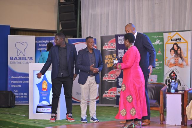 Samuel Bulenzi Isiko, the Stanbic Bank Head of Client Coverage recieving the award from Hon. Amelia Kyambadde, looking on is Robert Mukiza the Director General of Uganda Investment Authority